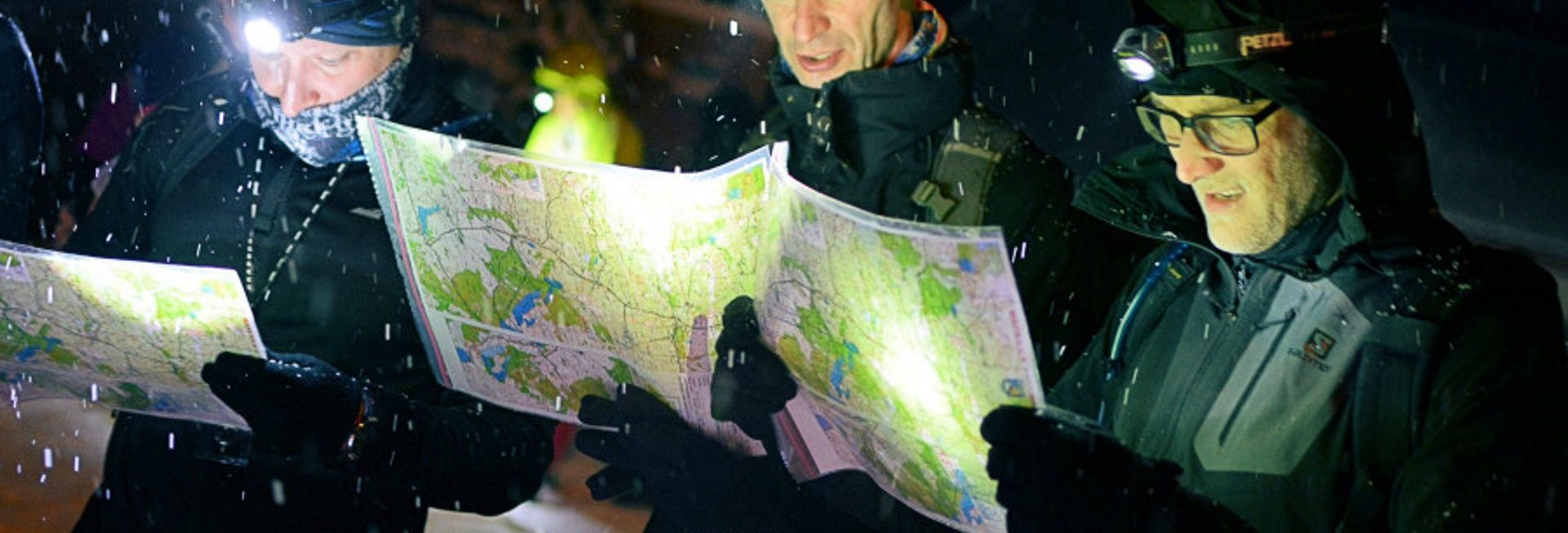 Zdjęcie przedstawia zawodników uczestniczących w zawodach, studiujących mapę zawodów.   