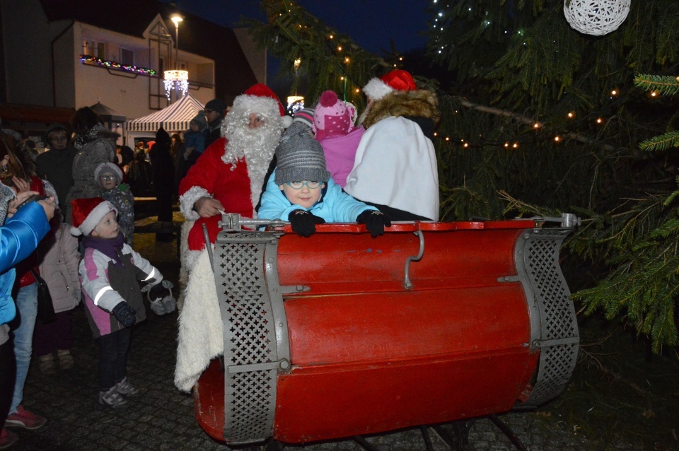 Zdjęcie przedstawia jedną z imprez na Fromborskim Rynku. Na zdjęciu Mikołaj z dziećmi na saniach.  