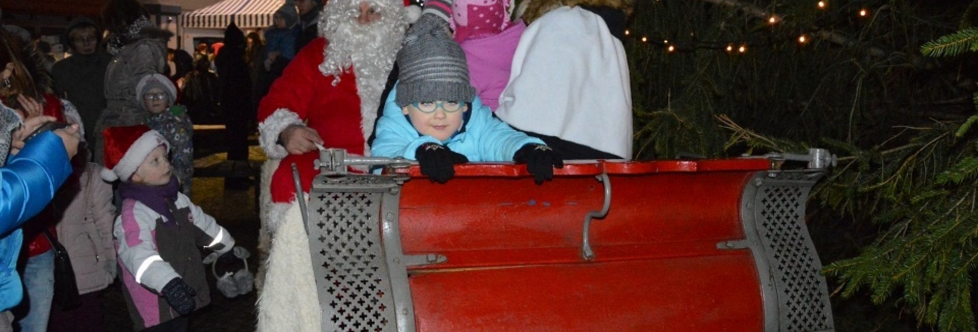 Zdjęcie przedstawia jedną z imprez na Fromborskim Rynku. Na zdjęciu Mikołaj z dziećmi na saniach.  