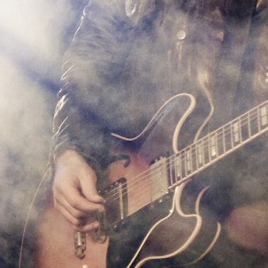 Zdjęcie ilustracja przedstawiającego gitarzystę podczas koncertu.