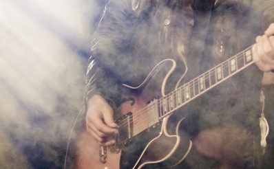 Zdjęcie ilustracja przedstawiającego gitarzystę podczas koncertu.