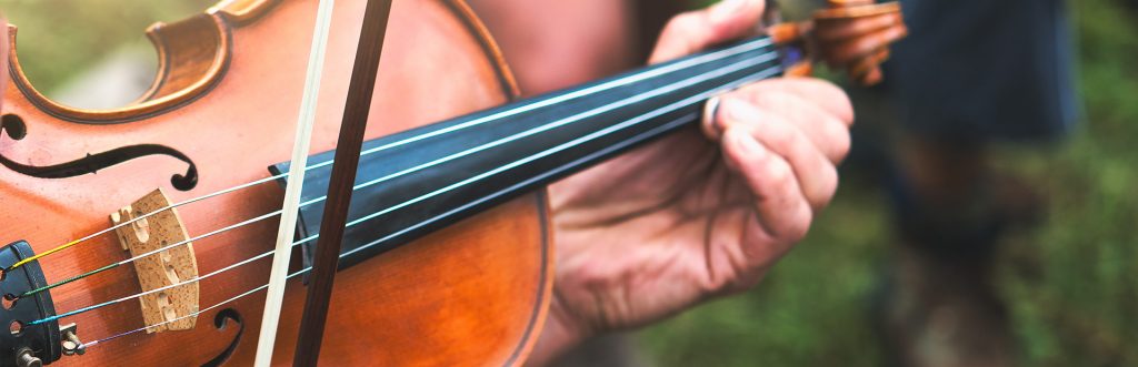 Skrzypce na których gra artysta trzymając jedną ręką smyczek a drugą instrument. 