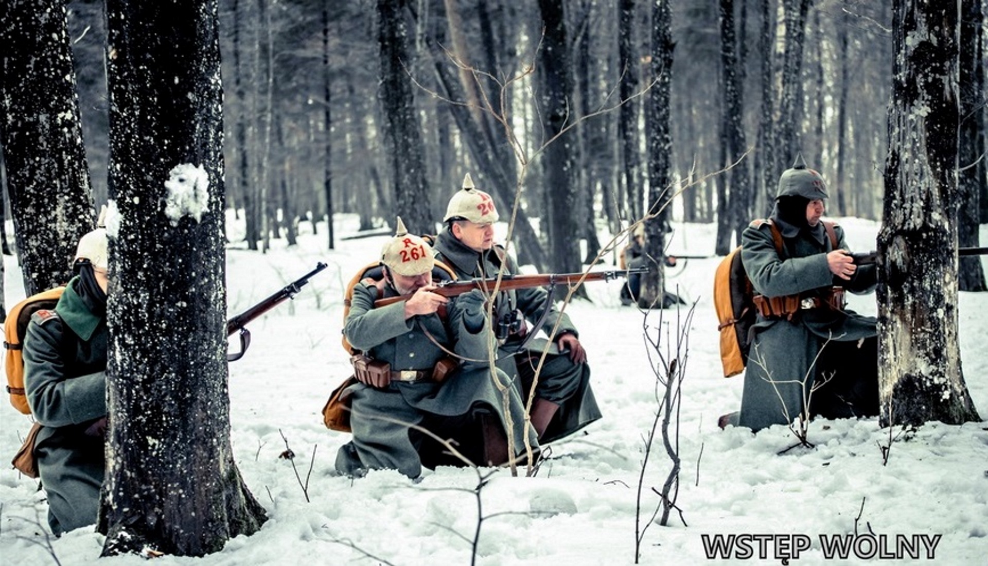 Zdjęcie zapraszające do Giżycka na Bitwę Zimową na Mazurach 2020. Zdjęcie przedstawia żołnierzy w lesie w mundurach z I Wojny Światowej podczas inscenizacji bitwy.