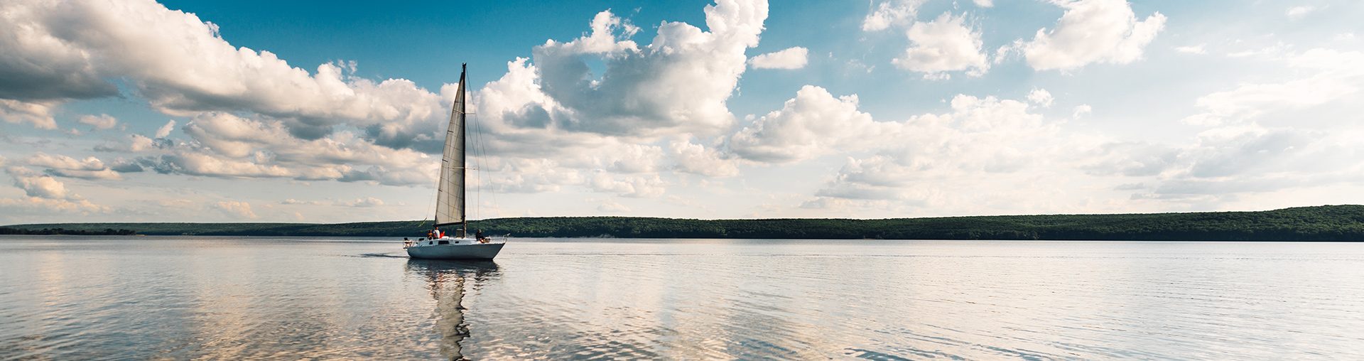 Samotna żaglówka pływającą po spokojnym mazurskim jeziorze. 