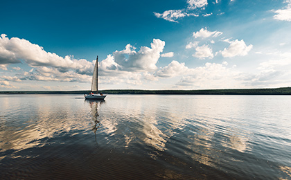 Samotna żaglówka pływającą po spokojnym mazurskim jeziorze. 
