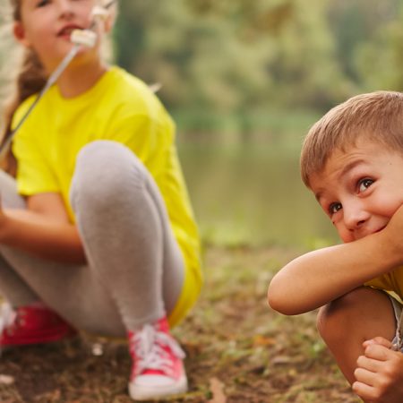 Na zdjęciu mała dziewczynka i chłopiec bawiące się w lesie.  