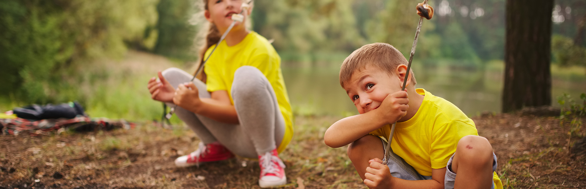 Na zdjęciu mała dziewczynka i chłopiec bawiące się w lesie.  