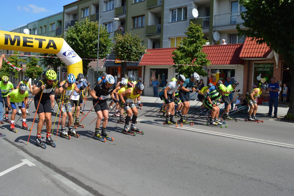 Zdjęcie zawodników na rolkach i nartorolkach, rozpoczynających na ulicach miasta Gołdapi start Letniego Biegu Jaćwongów.      