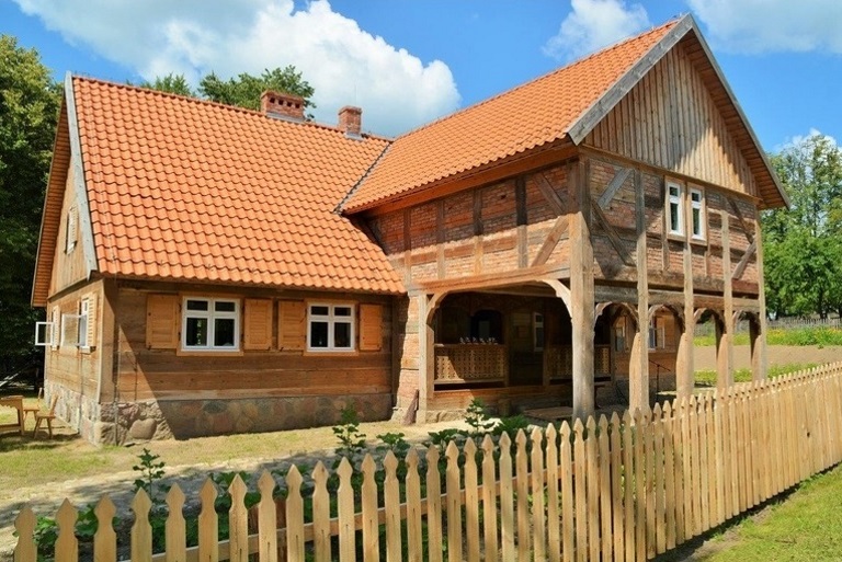 Zdjęcie chaty mazurskiej w Muzeum Budownictwa Ludowego w Olsztynku. Chata zbudowana z gankiem.    