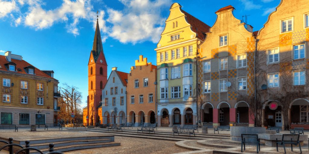 Plac na Starówce oraz zabytkowe budynki Starówki Miejskiej w Olsztynie podczas zachodzącego słońca.  