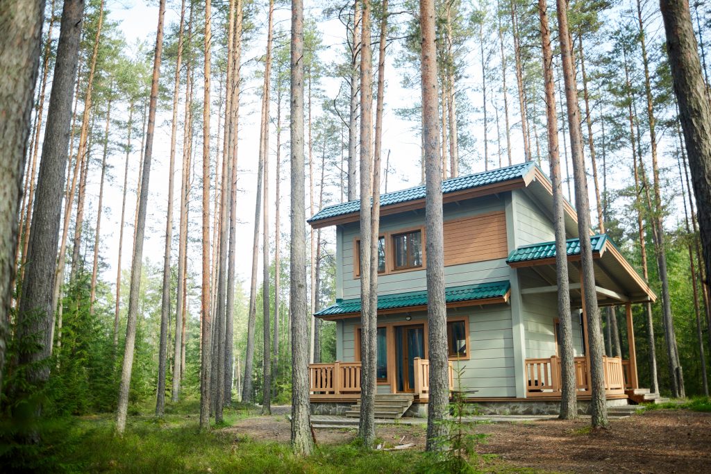 Zdjęcie jednopiętrowego letniskowego drewnianego domu w środku lasu.  