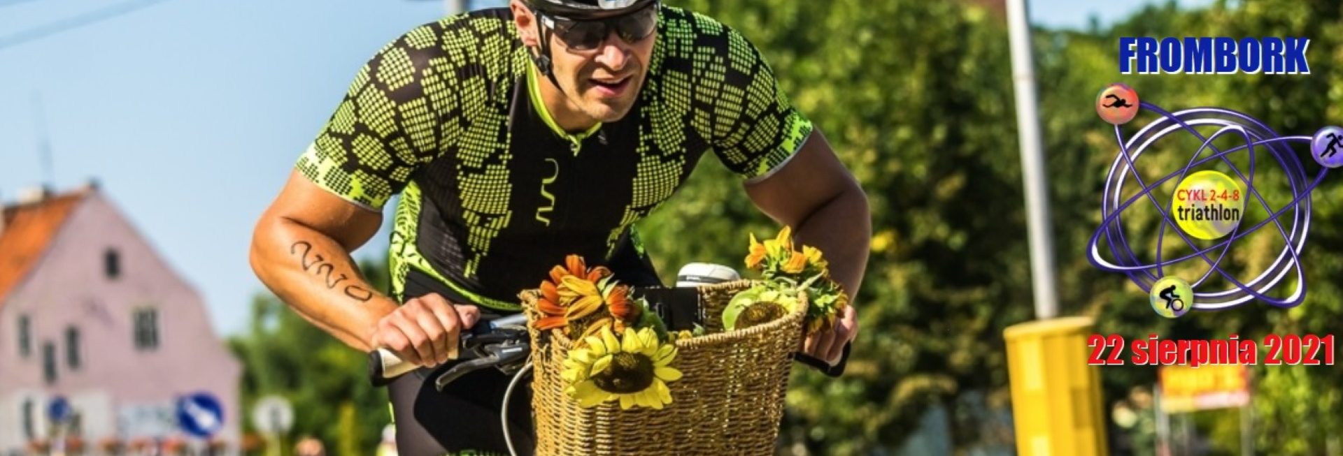 Zdjęcie zapraszające na cykliczne zawody Triathlon 2-4-8 Frombork 2021. Na zdjęciu zawodnik podczas zawodów jadący na rowerze. 