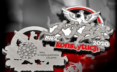 Na zdjęciu przygotowany medal zawodów które odbędą się w Olsztynie 1 maja 2021 r., 1. edycja Olsztyńskiego Biegu Konstytucji 3 maja – Olsztyn 2021. Na medalu wygrawerowane biegnące postacie a nad nimi orzeł.