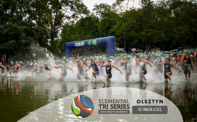 Zdjęcie zapraszające do Olsztyna na zawody Triathlon Elemental Tri Series Olsztyn - 2021. Na zdjęciu widzimy start zawodników nad jeziorem Ukiel, którzy rozpoczynają rywalizację od pływania.