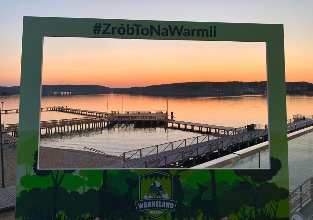 Plakat - zdjęcie zapraszające do Olsztyna na 5. edycję Wiosennego Warneland Ultramaratonu Warmińskiego Olsztyn 2023.